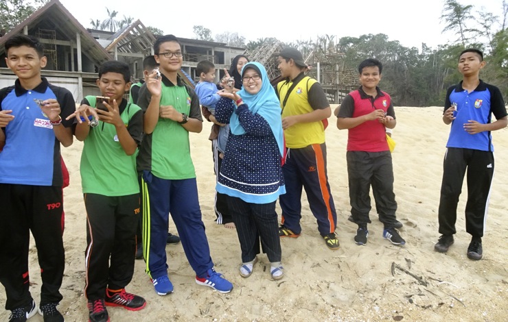 Students and teachers from S.M.K. Seri Nilam about to release newly emerged sea turtle hatchlings into the sea.